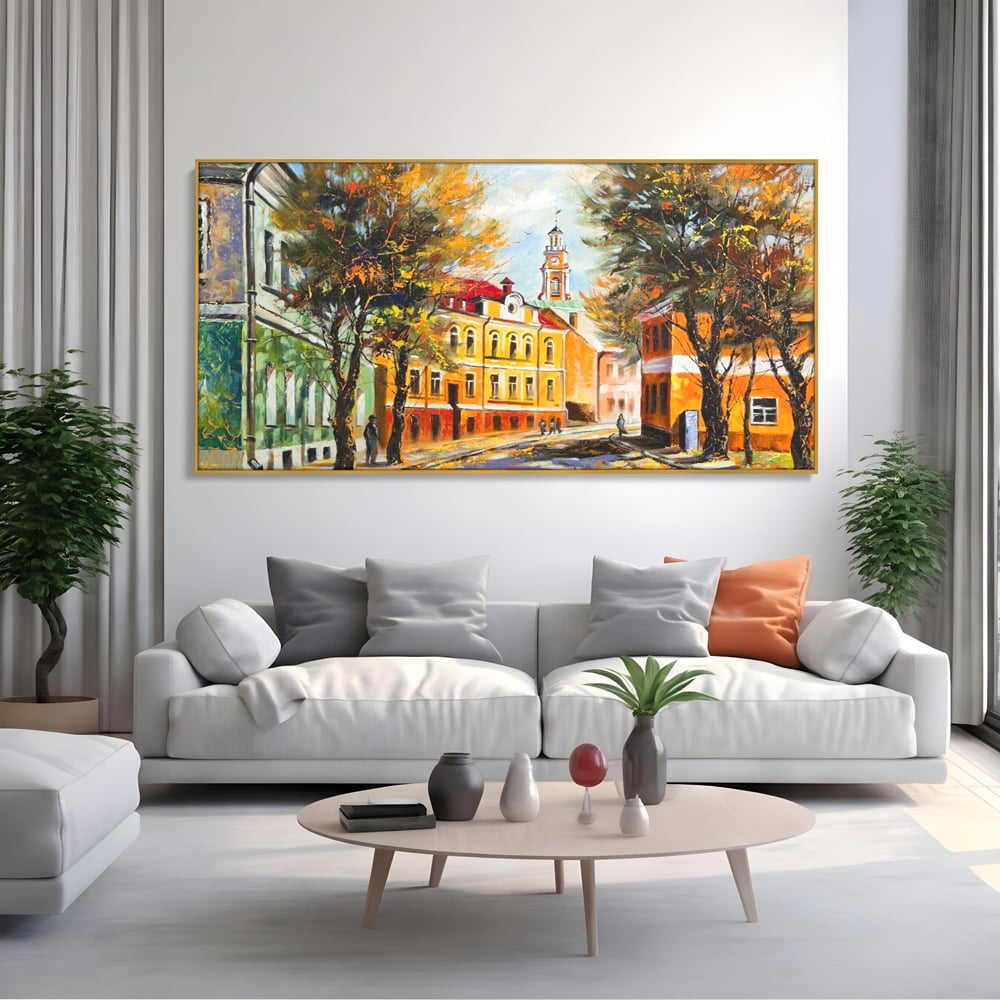 Tablou canvas cu pictura stradala cu peisaj de toamna, in rama de aluminiu auriu, pe perete intr-un living